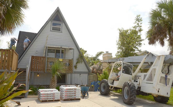 Roofers work on the roof of Louis Mastellone's St. Augustine Beach home on Monday, September 30, 2013.