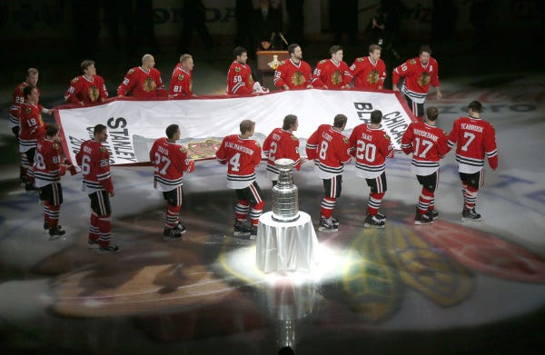 Banner night in Chicago: Members of the Chicago Blackhawks carry the championship banner past the Stanley Cup during a ceremony for the defending champs before last night's season opener against the Washington Capitals.          See more on the NHL, Page C5.
