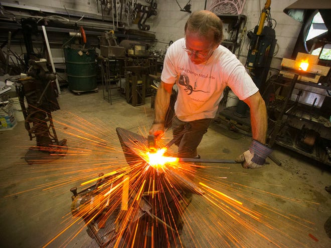 Ornamental Metal Smith Bill Roberts, forges two pieces of steel together while working in his shop, Custom Design Metal Arts, Thursday afternoon in Ocala. A show of forged and fabricated metal art is at Brick City Center for the Arts in Ocala through October.