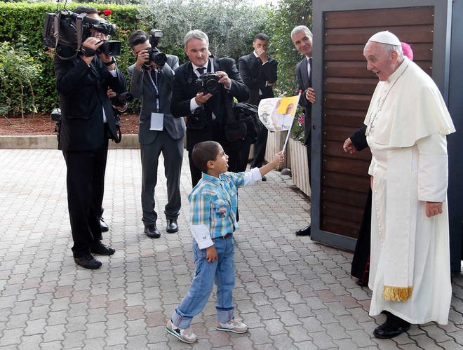 A child waves a flag as Pope Francis arrives at Caritas residence in Assisi on Friday. Francis made a pilgrimage to the hillside town of Assisi and the tomb of his namesake, St. Francis, the 13th-century friar who renounced a wealthy, dissolute lifestyle to embrace a life of poverty and minister to the most destitute. St. Francis was famously told by God to "repair my house." For more photos, go to lubbockonline.com and A-J on iPad.