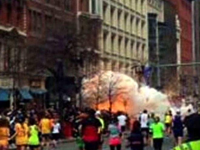 In this image from video provided by WBZ TV, spectators and runners run from what was described as twin explosions that shook the finish line of the Boston Marathon .