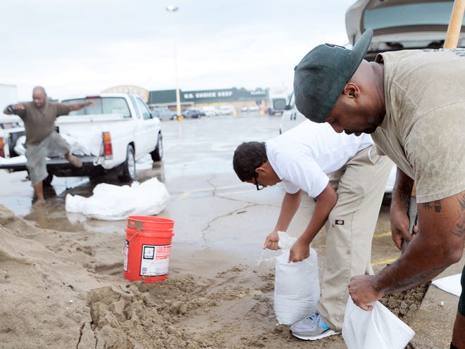 Cedric Johnson (right) and Devonne Perque fill sandbags Thursday at the Cannata's on West Park Avenue in Houma as Tropical Storm Karen moves through the Gulf of Mexico.