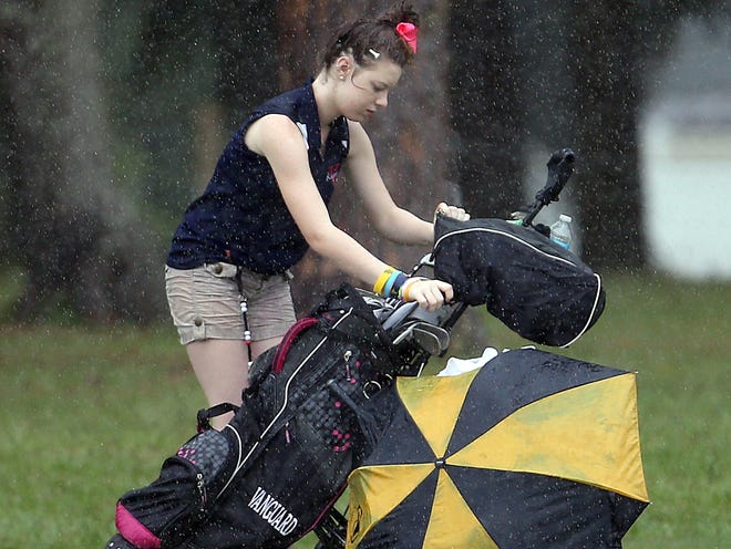 Vanguard’s Allexis French gets drenched as she tries to cover her clubs on the 16th hole at the MCIAC Golf Tournament on Monday. Heavy rains ended the chance for the tourney to finish.