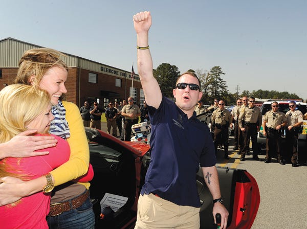 Then U.S. Army Spc. Josh Wetzel yells as he celebrates Oct. 19 on his first visit back to Glencoe after losing both legs in Iraq. Wetzel’s wife, Paige, in yellow, gets a hug. Wetzel was greeted by the high school marching band and a crowd of residents and first responders.