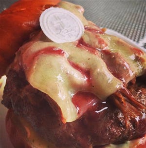 This undated photo provided by Kuma's Corner Restaurant shows the restaurant's October burger of the month Ghost, named after the Swedish heavy metal band who's members dress in religious robes and wear skeleton face makeup Thursday, Oct. 3, 2013, in Chicago. The Chicago restaurant has cooked up this controversial burger garnishing it with an unconsecrated communion wafer and a red wine reduction sauce. Luke Tobias, Kuma's Corner director of operations, said the restaurant never wanted to offend anyone. He said reaction has been a "mixed bag," but more positive than negative.