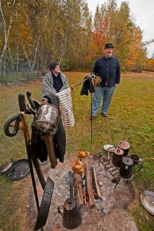 Dan Nason, left, and his father Roger Nason, stand around the cook's fire during a Civil War Encampment in New Durham Sunday.