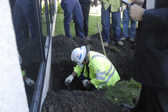 A National Grid employee uses special equipment to listen to the ground for sounds of a trapped animal outside the Utica National building on Tuesday, Oct. 8, 2013.