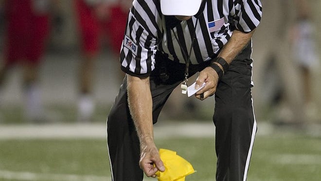 High school football official Bill Steffek picks up his penalty flag after making a call during the Bowie-Westlake game Sept. 27. Steffek, who has officiated two state championship games, has decided to retire after this season, his 50th.