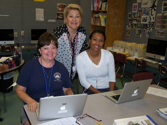 Tech Facilitator Heddie Carville works with teachers Patsy Lamothe and Tania Breaux during a technology in-service at Iberville Elementary. All teachers and administrators in the parish school system receive Mac book Pro laptops as part of the Iberville Parish Apple Initiative. Carville teaches strategies to help Iberville Elementary teachers use the computers in their classroom each month on “Tech Thursday.” Pictured are top, Heddie Carville and seated from left, Patsy Lamothe and Tania Breaux