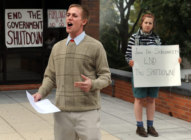 On Thursday, Framingham State University senior Roman Long of Falmouth protests the government shutdown outside the college center with junior Kendta Lohr of Southampton.