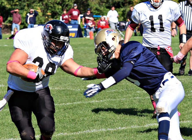 Dakota’s Tommy Bowers (class of 2010) tries to get extra yardage before Aquin’s Tyler Burkholder (class of 1999) takes him down Saturday during the alumni game at Conley Field in Freeport.
