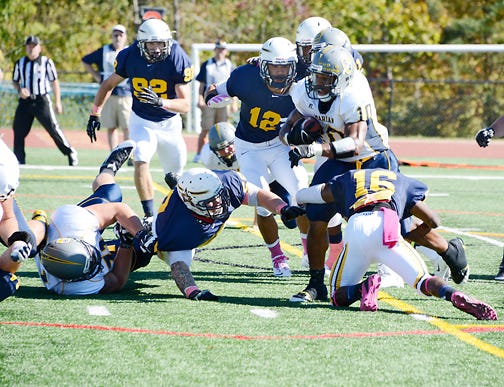 Siena Heights University’s DeShawn Gilbert (16) and Sederick Dunbar (12) wrap up Marian running back Tevin Lake for no gain in the first half of Saturday’s MSFA Mideast game in Adrian.