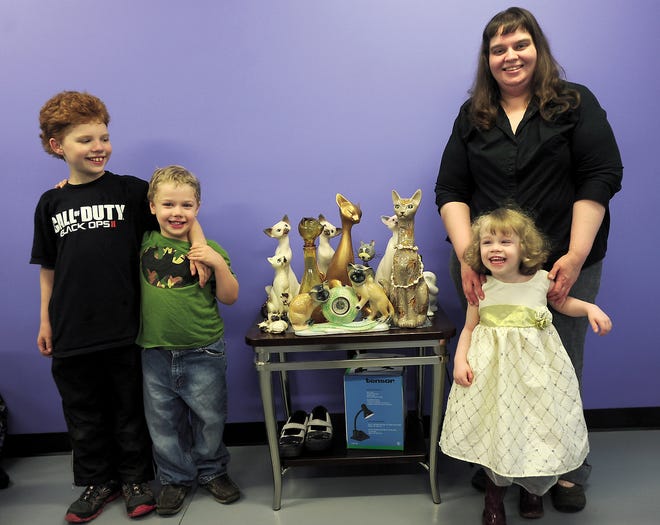 Mary Wills, and her 3 children Jesse Hays,10, Rowan Wills,6, and Olivia Hays,3 pose inside Wills' new nail salon The Cats Miaow in New Philadelphia. her origional salon burnt down in 2012. The cat figures where saved from the fire.