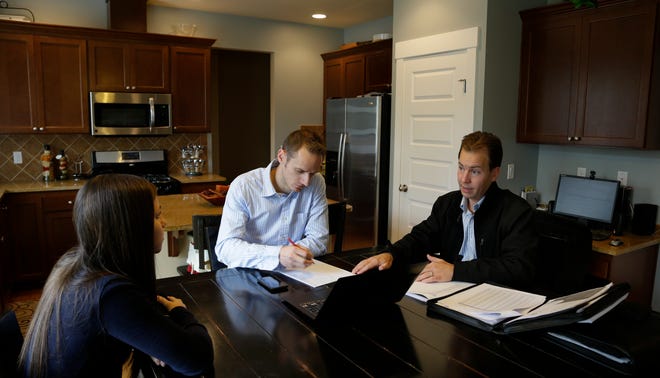 In this Thursday, Oct. 10, 2013 photo, insurance broker Jeff Lindstrom, right, meets with Brandi and Darren Litchfield to discuss health insurance plan options, at their home in the Seattle suburb of Bothell, Wash. Darren works for a startup company that doesn't yet offer an employee insurance plan, so they invited Lindstrom to outline the options of different healthcare plans that he offers as a broker.