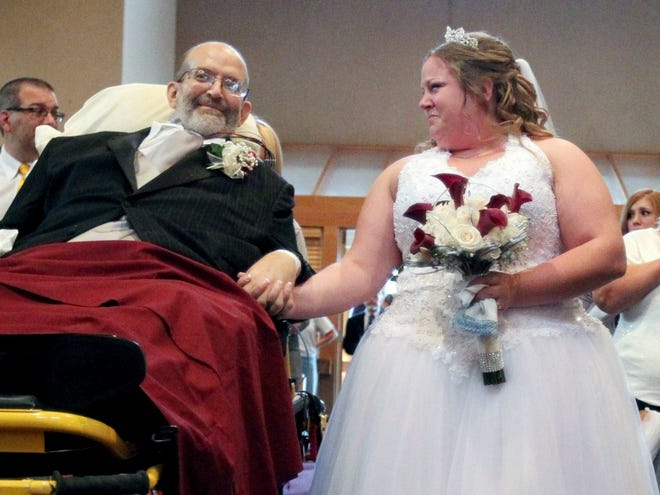 Bride Sarah Nagy, right, begins to cry as she is escorted by her father, Scott, down the aisle during her wedding ceremony Oct. 12, 2013 at First Lutheran Church in Strongsville. University Hospital sent a medical team along with Scott who is bound to his bed and the ambulance ride to the church was donated by Physicians Medical Transport.