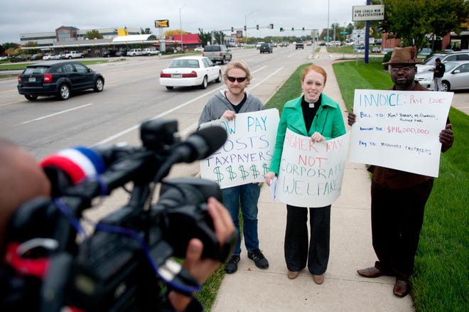 From left, Danny Vuyk, the Rev. Molly Housh Gordon and James Brown speak to reporters Tuesday outside the Taco Bell on Nifong Boulevard. The trio was highlighting a new report that says low wages and lack of benefits in the fast-food industry lead workers to use public assistance programs at a higher level than other workers.