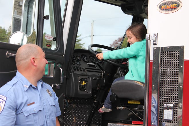 Riley F, 3, enjoys sitting in the drivers seat of Engine 5, while Firefighter Farland looks on.
