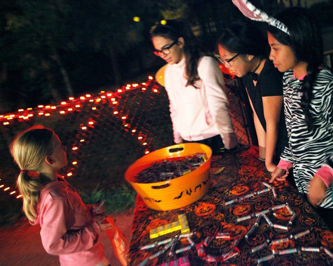 Six year-old Lily Gonet, left, stops by one the of the trick-or-treat stations at the Boo at the Zoo at Buttonwood Park Zoo.