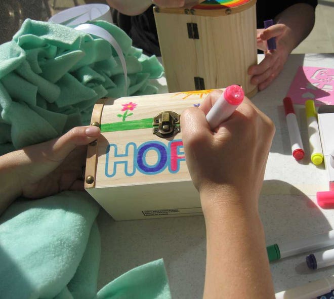 McKesson employee Joy Crutchfield writes a note of encouragement to be included in a small wooden hope chest. The chests are part of care packages for U.S. cancer patients undergoing chemotherapy.