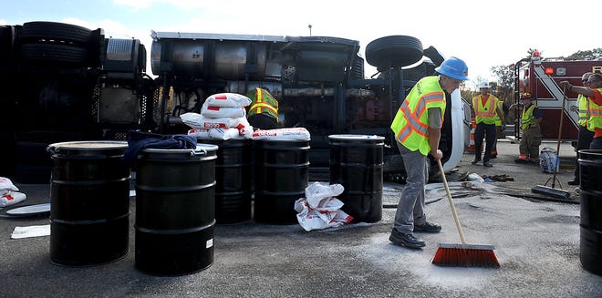 Workers clean up after a tractor trailer overturned on the ramp to the Mass Pike West in Hopkinton this afternoon. The tractor trailer was exiting Rte. 495 South. The ramp to the Mass Pike off Rte. 495 South was closed for about an hour and traffic was backup about a mile on Rte. 495 North. Traffic on the Mass Pike was not affected.