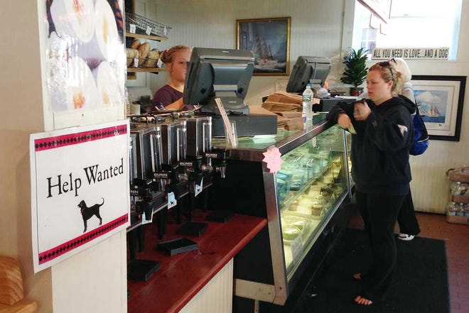 In this Tuesday, Oct. 15, 2013 photo, a "Help Wanted" sign is displayed at the Black Dog Bakery in Tisbury, Mass., as a customer is served on Martha's Vineyard island. Applications for U.S. unemployment benefits dropped 15,000 to a seasonally adjusted 358,000 last week, though the figure was distorted for the second straight week by California's efforts to clear backlogged claims. The Labor Department says the less volatile four-week average rose 11,750 to 336,500. (AP Photo/Mark Lennihan)