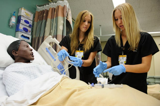 Twin sisters Shay, left, and Shelby Noll work with mannequins in the simulation lab at the University of Missouri Sinclair School of Nursing this week.