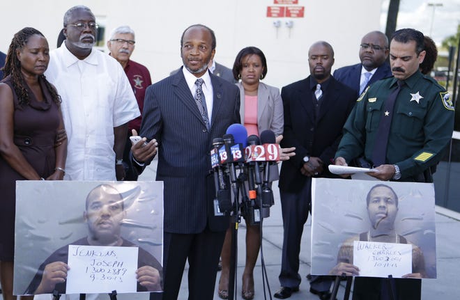 Lillie Danzy, front left, mother of escaped inmate Charles Walker, with her husband Jeff Danzy, second from left, and family supporters and members of the Orange County Sheriff's Office listen as Henry Pearson, center, uncle of escaped inmate Joseph Jenkins, makes a plea for his nephew to turn himself in to authorities during a news conference in Orlando Saturday. Joseph Jenkins, photo front left, and Charles Walker, photo front right, two convicted killers freed by bogus paperwork, are at large