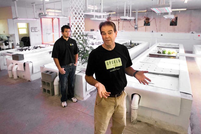 Chris Mammoliti, right, explains the workings of an aquaponics facility operated by Trash Mountain Project in North Topeka. Looking on is Isaac Tarwater. Aquaponics allows plants to be grown without soil.