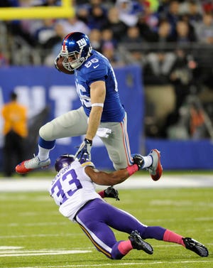 New York tight end Bear Pascoe leaps over Minnesota's Jamarca Sanford during the first half Monday night. The Giants broke through after losing their first six games.