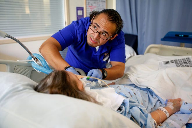 David Fuentes, a graduate of the nursing program at UCLA, tends to a patient at the UCLA Medical Center in Santa Monica.