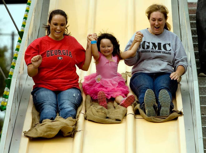 Jessica Osborne (from left), Ellye Osborne, 3, and Krista Johnson hold hands as they make their way down the Rapid Slide at the Jack O'Lantern Jubilee held in North Augusta last year. This year's event will be 10 a.m. to 8 p.m. Saturday along Georgia Avenue and Jackson Square.