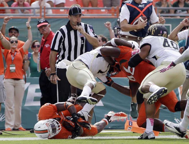 Alan Diaz Associated Press Miami's Duke Johnson (bottom left) scores a touchdown against Wake Forest during the fourth quarter of Saturday's game in Miami Gardens.