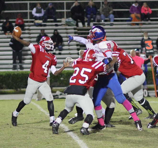 Jacksonville quarterback Exelman Adams prepares to throw the ball as teammate Jermaine Linton (25) blocks West Craven's Malik Adams during the teams' Coastal 3-A Conference game Friday night. The Cardinals lost 27-7 on homecoming in a battle for second place in conference.