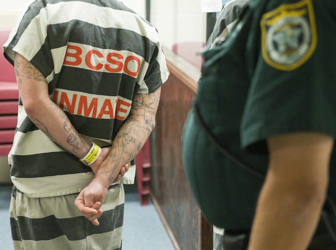 An inmate holds his arms behind his back while speaking with a judge via teleconference during first appearances at the County Jail in Panama City on Thursday.