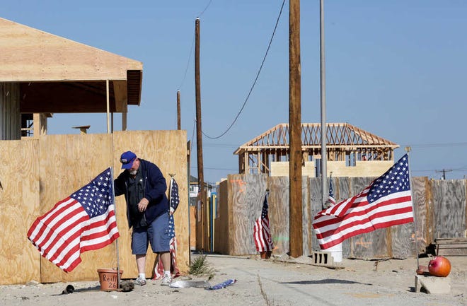 Tom Hammill places an American flag Tuesday at a building site in the Breezy Point neighborhood in the Queens borough of New York, a year after Superstorm Sandy struck. A firestorm spread across the beachfront neighborhood during the storm, burning more than 100 homes, including Hammill's. Behind him are homes that are being rebuilt.