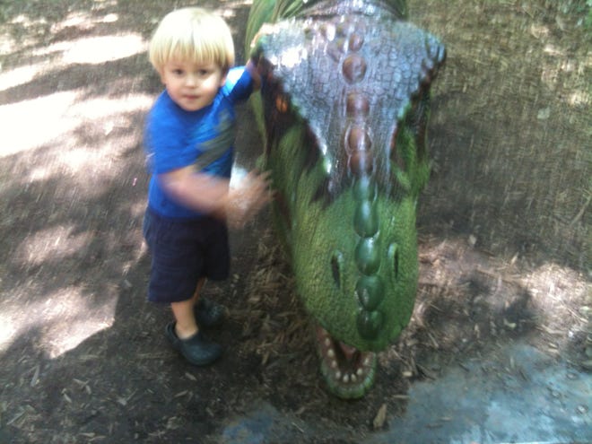 Jett Jurney poses with one of the dinosaurs at the N.C. Zoo exhibit in Asheboro in May 2012.