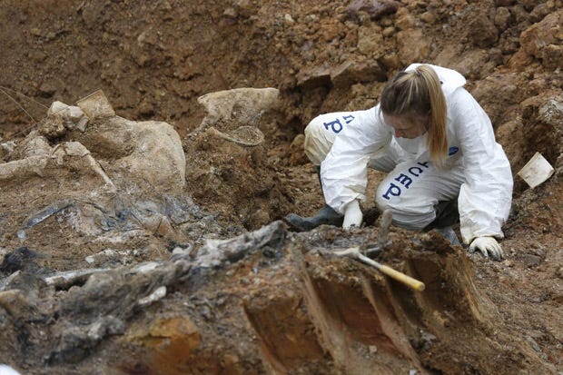 Forensic experts, members of the International Commission on Missing Persons (ICMP), and Bosnian workers search for human remains at a mass grave in the village of Tomasica, near the Bosnian town of Prijedor.