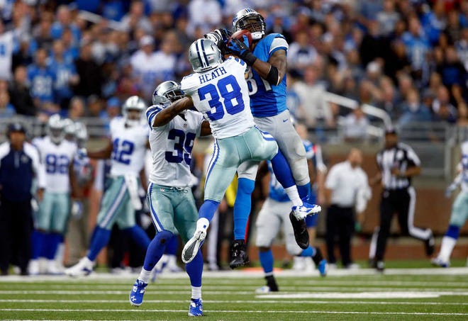 Detroit Lions wide receiver Calvin Johnson (81) catches a 54-yard reception against Dallas Cowboys cornerback Brandon Carr (39) and defensive back Jeff Heath (38) in the fourth quarter of an NFL football game in Detroit, Sunday, Oct. 27, 2013. (AP Photo/Rick Osentoski)