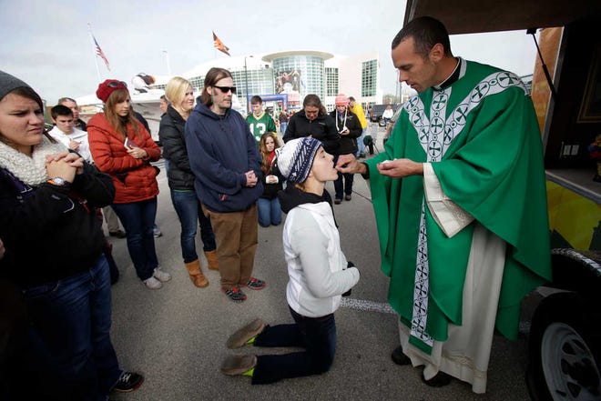 Emily Dalsky, center, receives communion from the Rev. Quinn Mann during Mass prior to a Green Bay Packers football game in Ashwaubenon, Wis. (AP Photo/The Post-Crescent, Dan Power)