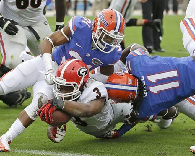Georgia running back Todd Gurley (3) dives over the goal line for a touchdown past Florida linebacker Neiron Ball (11) and defensive back Cody Riggs (31) during the first half of an NCAA college football game in Jacksonville Saturday.