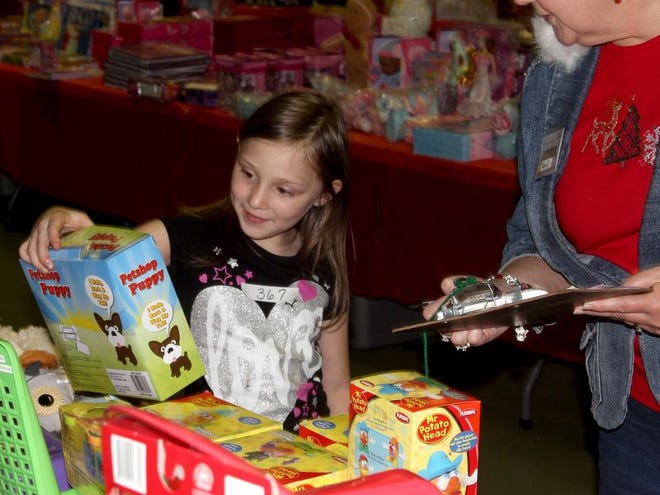 With help from a volunteer, a youngster selects an age-appropriate gift for a sibling during last year’s Giving Store in Cattleman’s Hall at the Flagler County Fairgrounds.