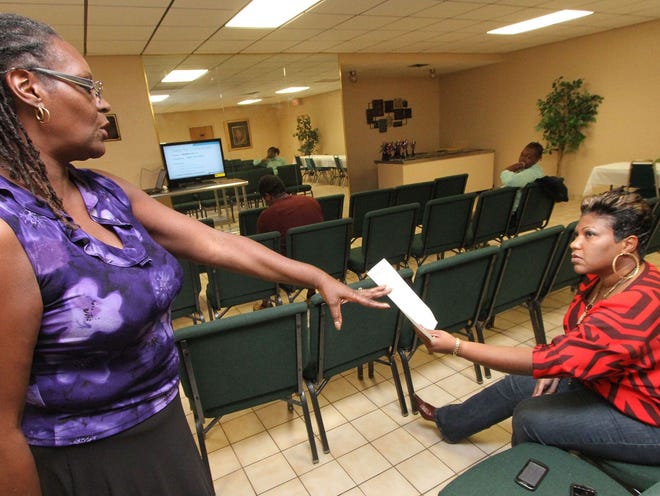 Navigator Alyce Shelton hands Michele Gilbert some information as she talks to a group about the Affordable Health Care Act recently at Daytona Deliverance Church.