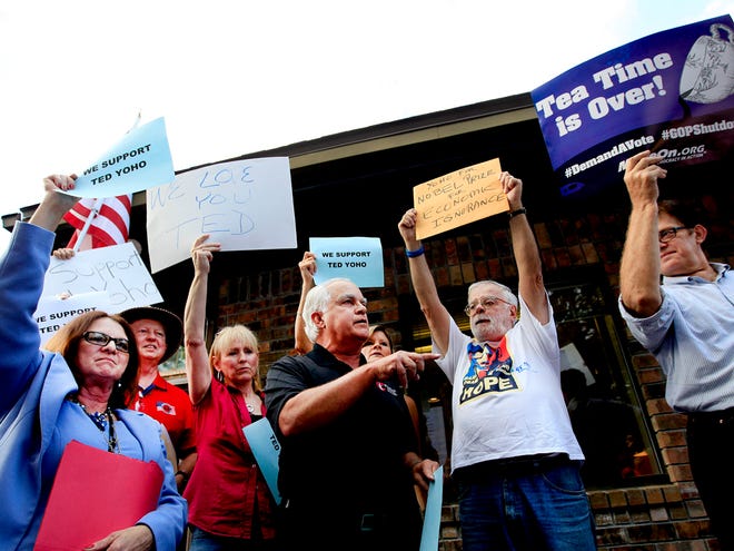 John Pastore, a supporter of Congressman Ted Yoho, center, speaks to the crowd during a protest about the government shutdown outside Yoho's offices in this Wednesday, Oct. 16, 2013 file photo in Gainesville.