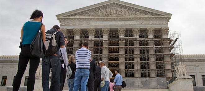 This Oct. 7, 2013 photo shows people waiting in line to enter the Supreme Court in Washington. The Supreme Court asks God for help before every public session. Now the justices will settle a dispute over prayers in the halls of government.