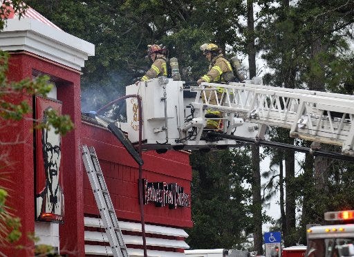 Firefighters work to put out a fire at the KFC at 3430 University Blvd. S. Monday.