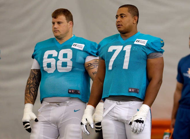 Miami Dolphins guard Richie Incognito (68) and tackle Jonathan Martin (71) stand on the field during an NFL football practice in Davie, Fla. Two people familiar with the situation say suspended Dolphins guard Incognito sent text messages to teammate Jonathan Martin that were racist and threatening.