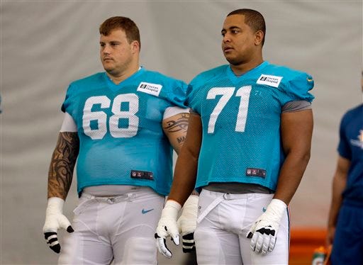 In this July 24, 2013 file photo, Miami Dolphins guard Richie Incognito (68) and tackle Jonathan Martin (71) stand on the field during an NFL football practice in Davie, Fla. Two people familiar with the situation say suspended Dolphins guard Incognito sent text messages to teammate Jonathan Martin that were racist and threatening. The people spoke to The Associated Press on condition of anonymity because the Dolphins and NFL haven't disclosed the nature of the misconduct that led to Incognito's suspension. Martin remained absent from practice Monday, Nov. 4, 2013, one week after he suddenly left the team. (AP Photo/Lynne Sladky, File)