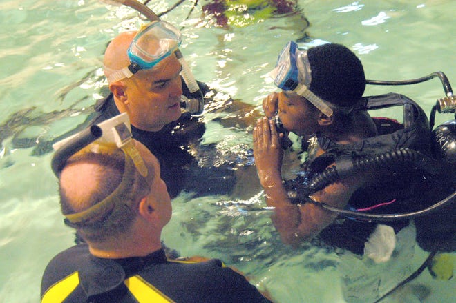 Police dive team member Steven Crowinshield, left, and dive team commander Matthew McCaffrey assist Kyeshaun Michel with his scuba gear at the Boys & Girls Club in Taunton.