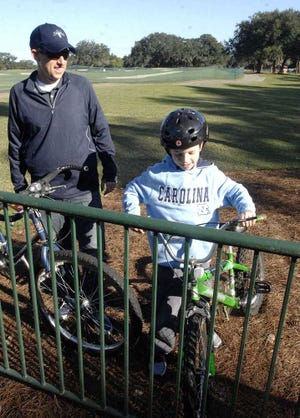 Colby Slaughter and his son Tate, 8, put their bikes in a rack after riding them to the McGladrey Classic on Friday.