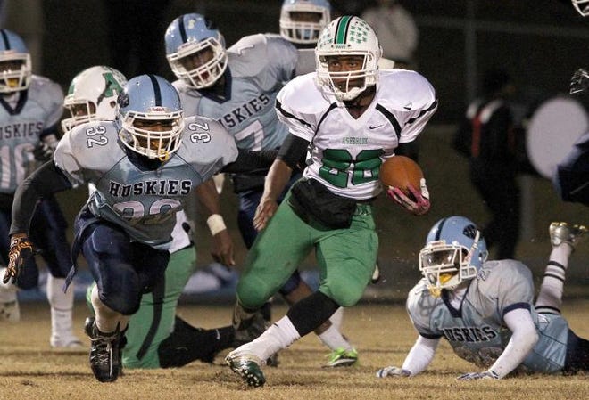 Ashbrook's Z'Andre Givens runs upfield as Hunter Huss' Brian Goodson, 32, gives chase during the Green Wave's 24-17 win over the Huskies Friday night.